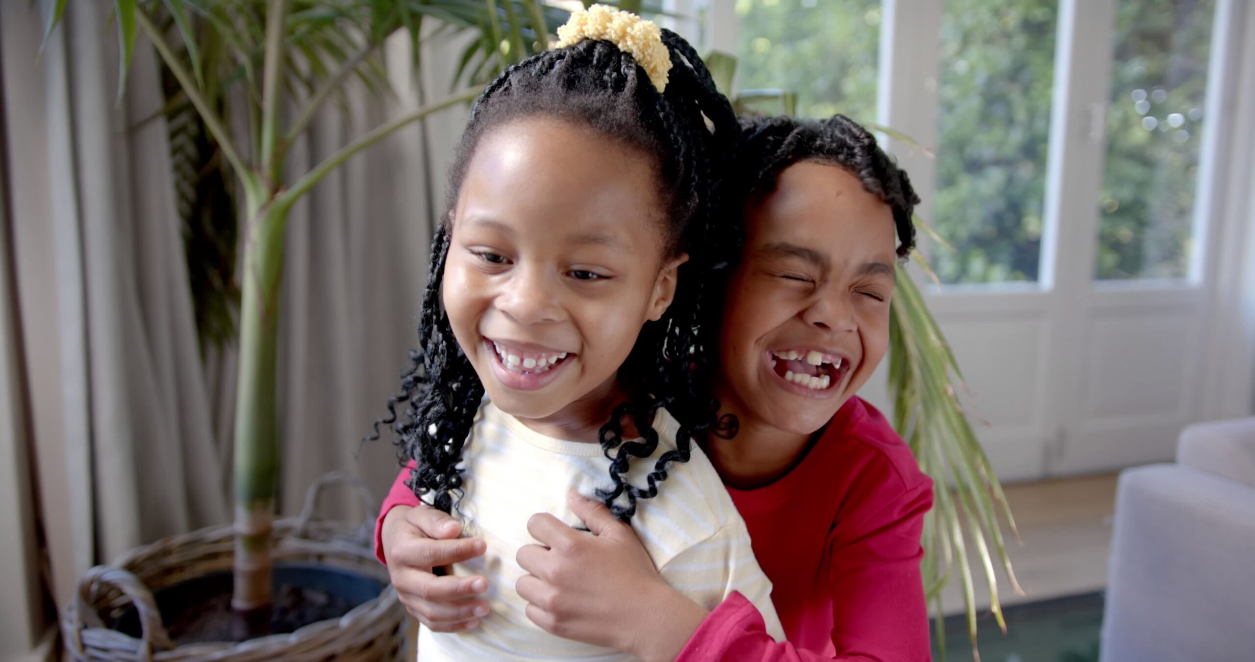 happy african american brother and sister laughing and embracing in sunny living room SBI 350772470